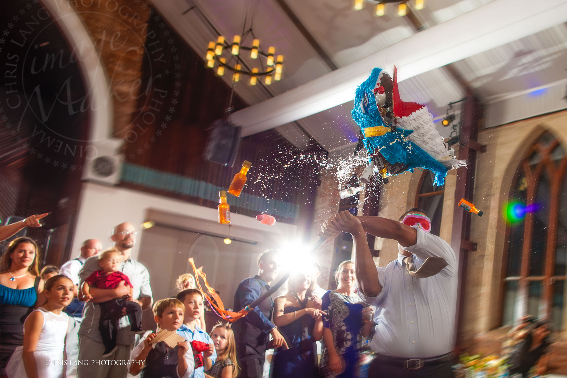 Fun wedding picture of a groomsman hitting a pinata and bottles of alcohol falling out.  Brooklyn Arts Center Weddings
