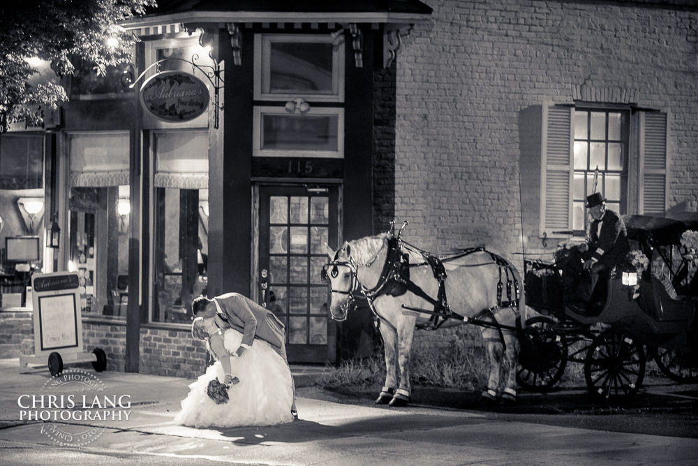 bride and groom kissing in front of horse and cariage -  Wilmington wedding photography - night wedding photography - evening wedding photos- bride - groom -  night time wedding photo ideas - low light wedding photography - Wilmington NC Wedding Photographers